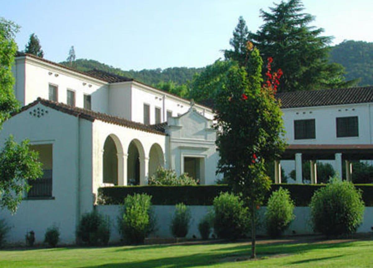White multi-story buildings and a round tower at the Veterans Home of California in Yountville, with lawns and an American flag